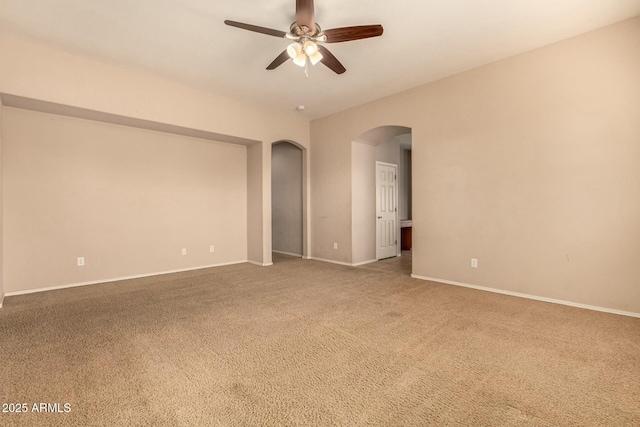 empty room with arched walkways, ceiling fan, carpet, and baseboards