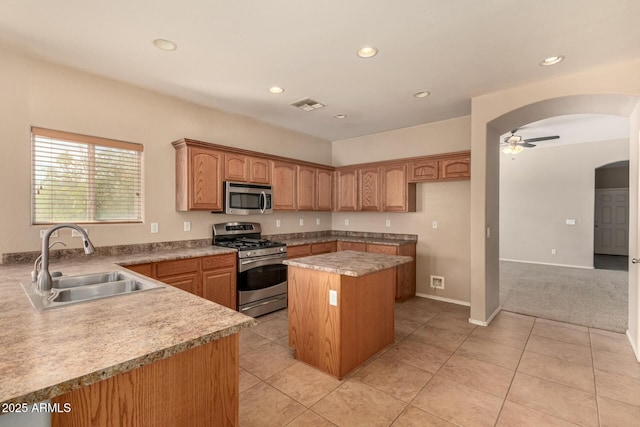 kitchen with stainless steel appliances, a kitchen island, visible vents, a sink, and light countertops