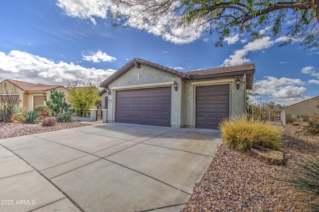 exterior space featuring stucco siding, driveway, a tile roof, fence, and an attached garage