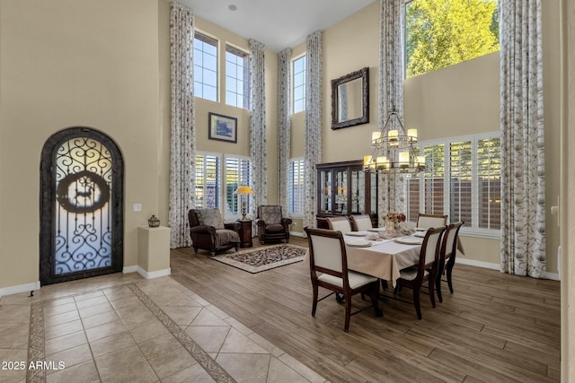 dining space featuring a towering ceiling, a healthy amount of sunlight, and an inviting chandelier