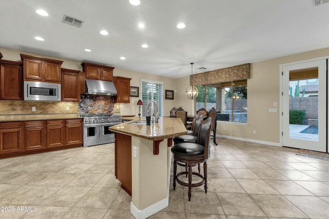 kitchen with an inviting chandelier, sink, a breakfast bar area, light stone counters, and stainless steel appliances