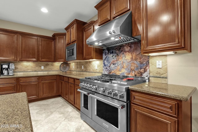 kitchen with decorative backsplash, light stone countertops, exhaust hood, and appliances with stainless steel finishes