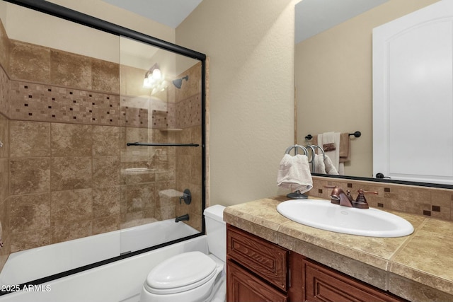 full bathroom with vanity, toilet, bath / shower combo with glass door, and tasteful backsplash