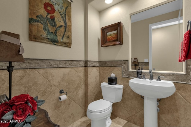 bathroom with sink, toilet, and tile walls