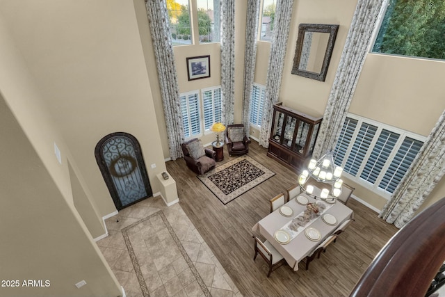 living room with a high ceiling, light hardwood / wood-style flooring, plenty of natural light, and a notable chandelier