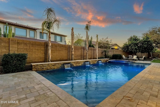 pool at dusk featuring pool water feature and a patio area