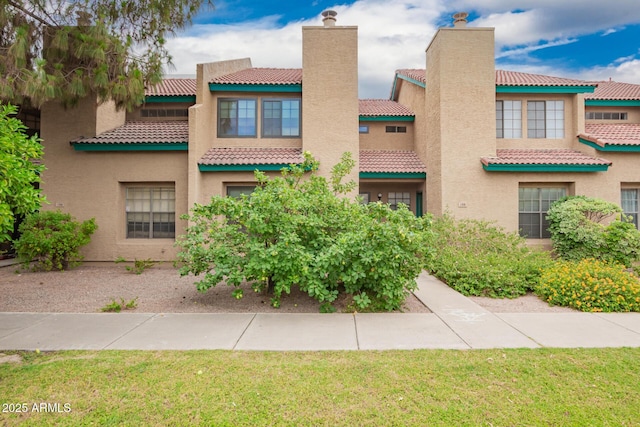 225 W 1st St Unit 107, Mesa, AZ 85201 - view of front of home with a tiled roof, stucco siding, a chimney, and a front yard