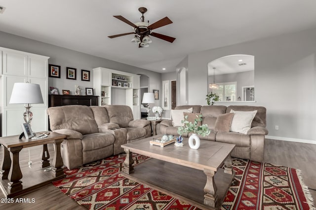 living area featuring arched walkways, wood finished floors, visible vents, and baseboards