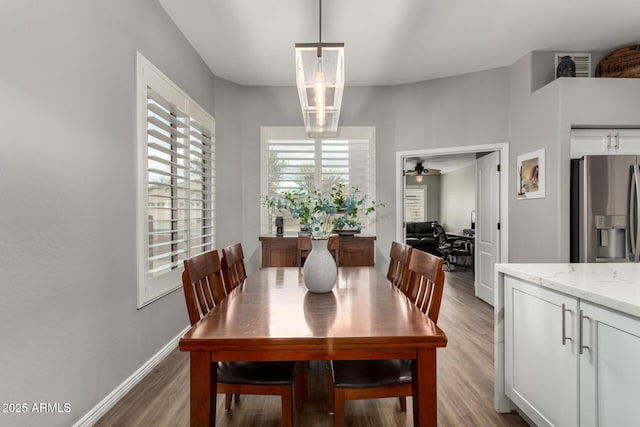 dining area with light wood-style flooring, baseboards, and a notable chandelier