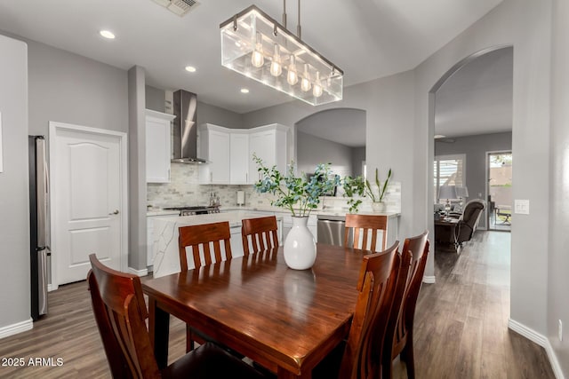 dining area with arched walkways, dark wood-style flooring, visible vents, and baseboards