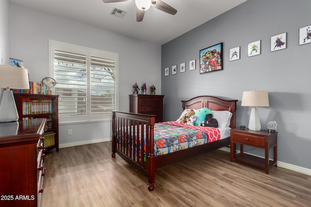 bedroom featuring a ceiling fan, visible vents, baseboards, and wood finished floors