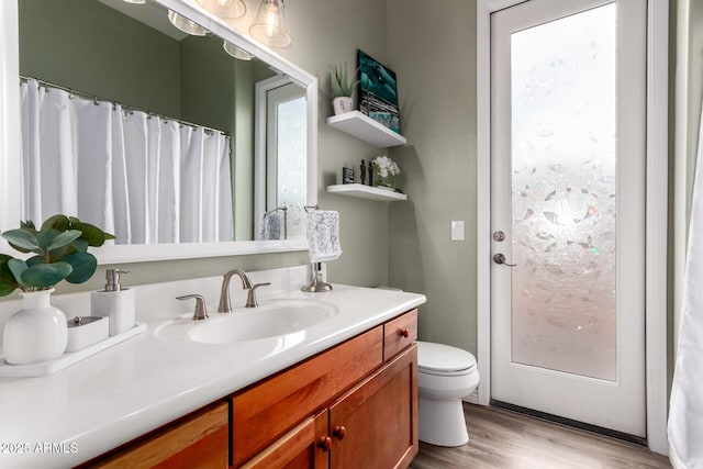 full bath with toilet, wood finished floors, and vanity