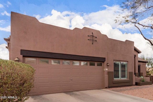 pueblo revival-style home with a garage, concrete driveway, and stucco siding