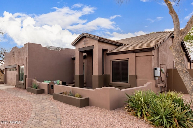 view of front facade with a garage, fence, and stucco siding