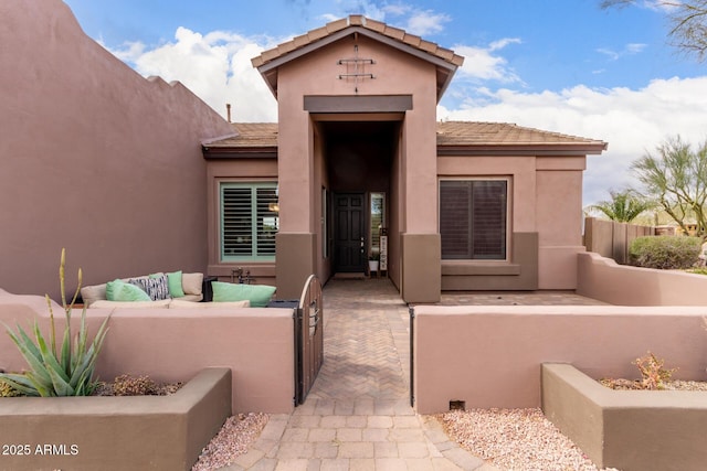 view of exterior entry with stucco siding, a patio, and an outdoor hangout area