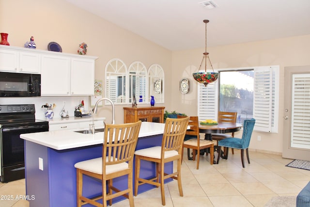 kitchen featuring a center island with sink, decorative light fixtures, black appliances, white cabinets, and sink