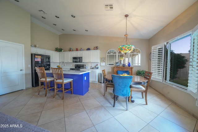 kitchen featuring light tile patterned floors, white cabinetry, a kitchen island with sink, hanging light fixtures, and black appliances