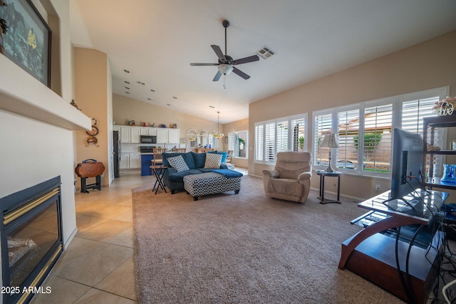 tiled living room with vaulted ceiling and ceiling fan with notable chandelier