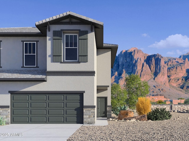 view of front of property with a garage, stucco siding, stone siding, a mountain view, and driveway