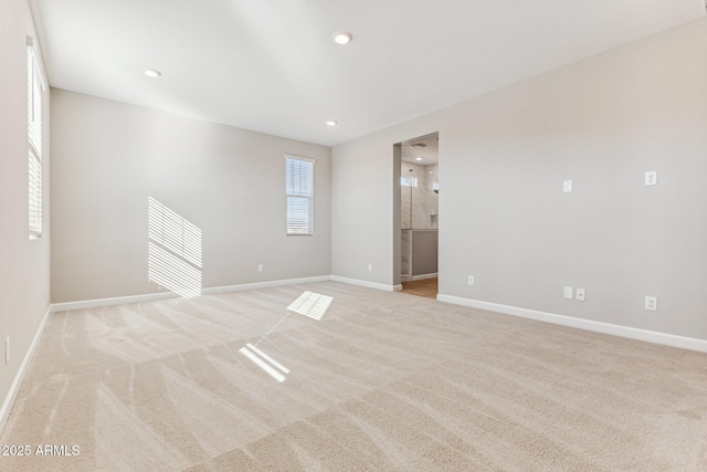spare room featuring baseboards and light carpet