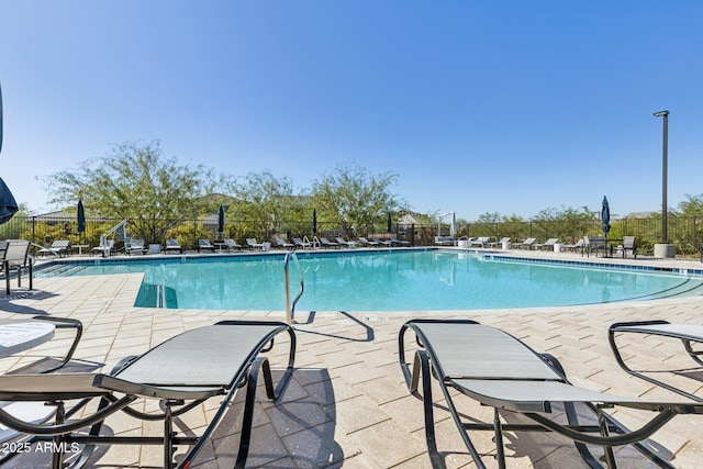 community pool with a patio area and fence