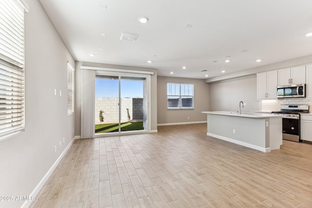 kitchen with tasteful backsplash, open floor plan, light wood-style floors, stainless steel appliances, and a sink