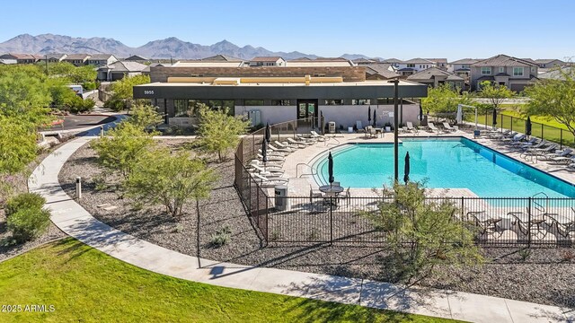 community pool with a patio, a residential view, fence, and a mountain view