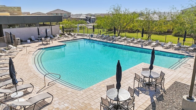 pool with a patio, a residential view, and fence