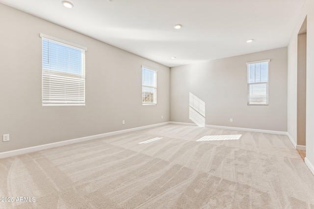 unfurnished room featuring light carpet and baseboards