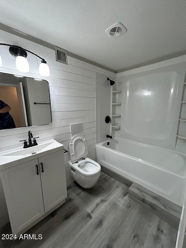 full bathroom with a textured ceiling, vanity, bathing tub / shower combination, hardwood / wood-style flooring, and toilet