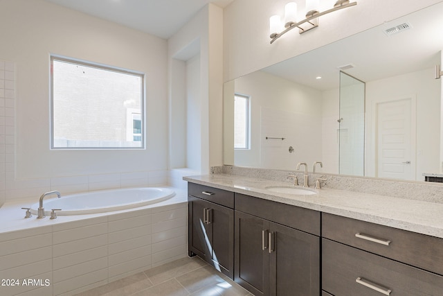 bathroom featuring tile patterned flooring, vanity, and tiled tub