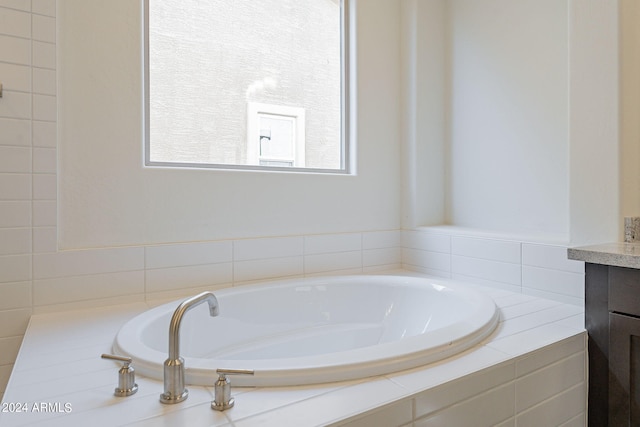 bathroom with tiled tub and vanity