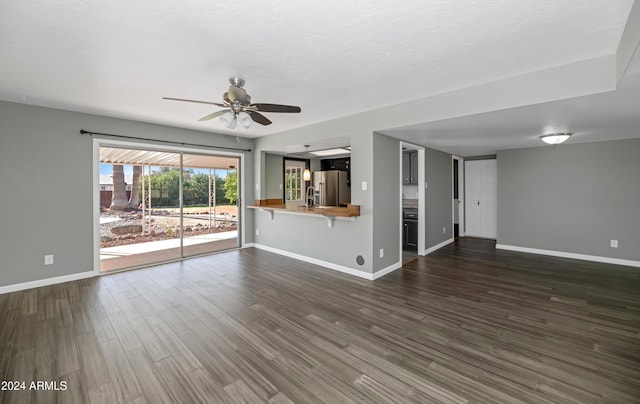 unfurnished living room featuring ceiling fan, dark hardwood / wood-style flooring, and sink