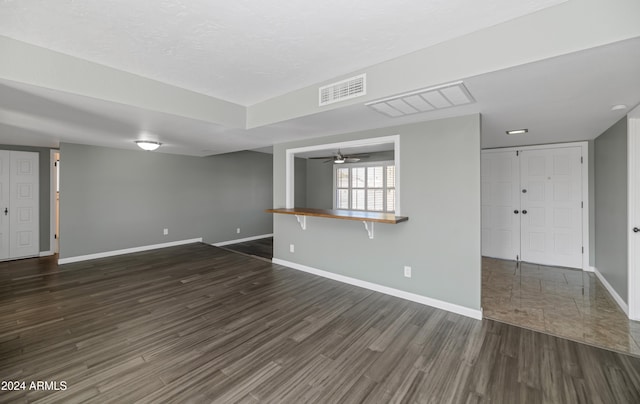 unfurnished living room with ceiling fan, dark wood-type flooring, and a textured ceiling