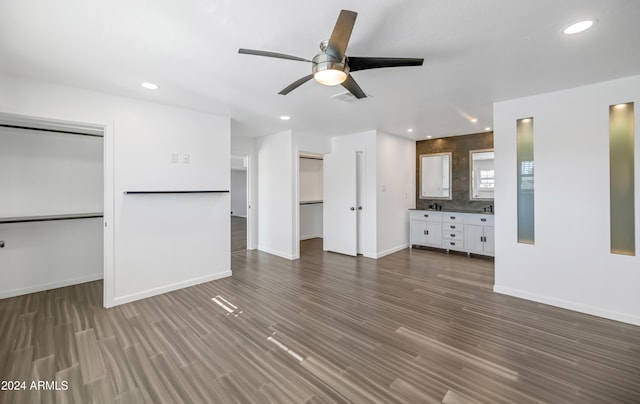 unfurnished living room featuring dark hardwood / wood-style floors, ceiling fan, and sink