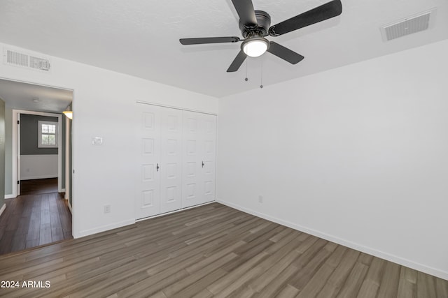 unfurnished bedroom with dark hardwood / wood-style floors, ceiling fan, and a closet