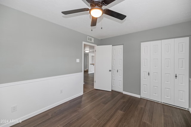 unfurnished bedroom featuring dark hardwood / wood-style floors, ceiling fan, a textured ceiling, and multiple closets