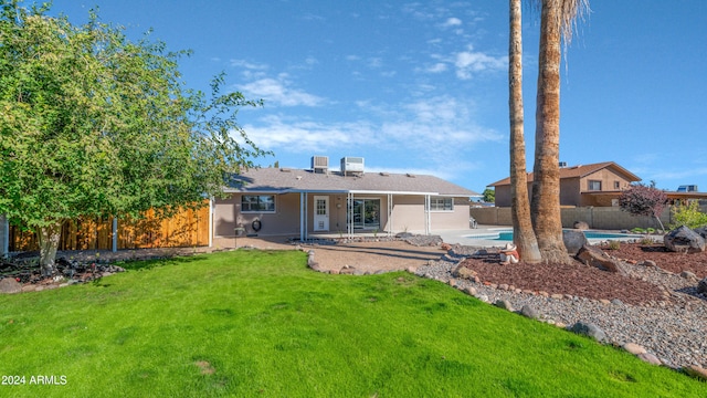 rear view of property featuring a fenced in pool, a patio area, and a yard