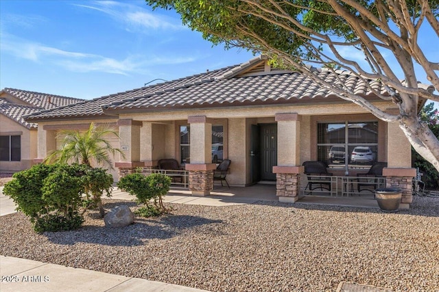 view of front of property featuring a tile roof, stucco siding, and a patio area
