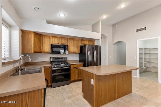 kitchen with stainless steel appliances, a sink, arched walkways, brown cabinetry, and lofted ceiling