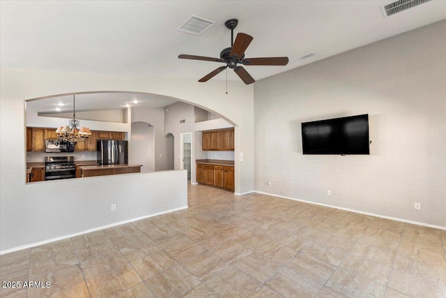 unfurnished living room with vaulted ceiling, ceiling fan, arched walkways, a chandelier, and baseboards