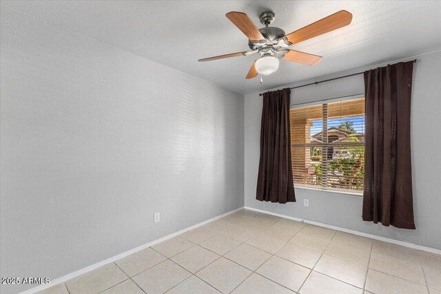 spare room featuring baseboards, ceiling fan, and light tile patterned flooring
