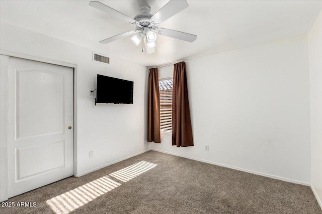 carpeted empty room with a ceiling fan and baseboards