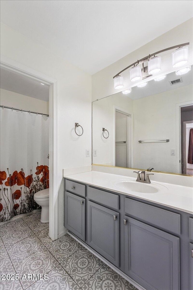 bathroom with toilet, vanity, and tile patterned flooring