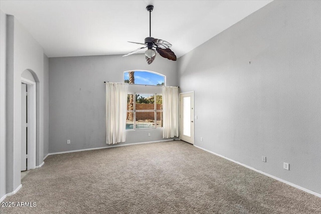 carpeted empty room with ceiling fan, baseboards, and high vaulted ceiling