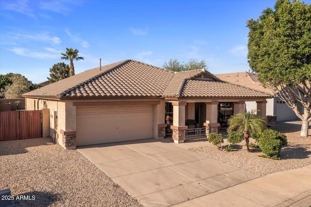 view of front of home featuring covered porch, stucco siding, a garage, and a tiled roof