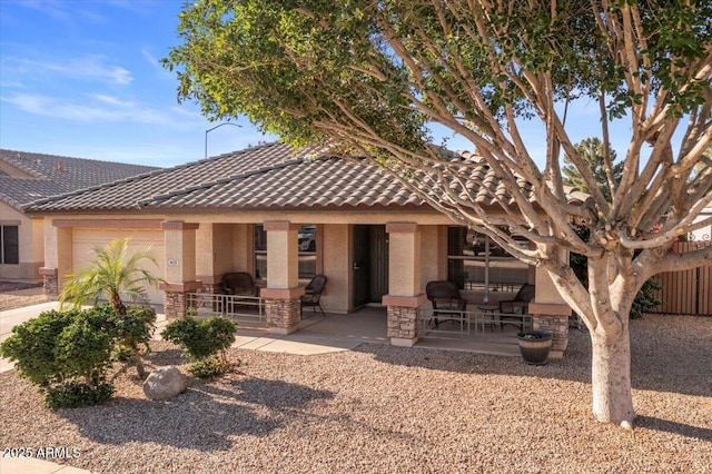 view of front of property with stucco siding, a garage, a tile roof, and a patio