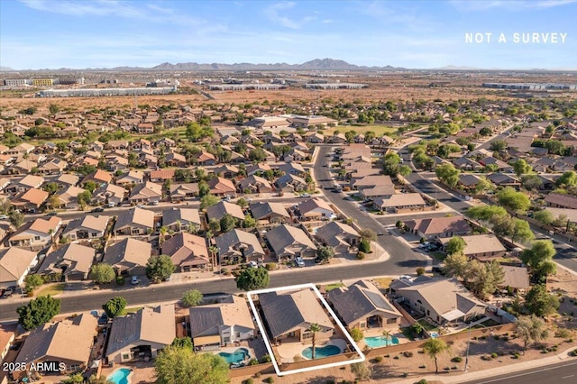 aerial view of property and surrounding area featuring a mountain backdrop, property parcel outlined, nearby suburban area, and a pool