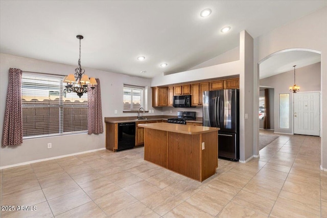 kitchen featuring black appliances, a chandelier, brown cabinets, a sink, and lofted ceiling