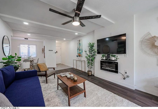 living room with ceiling fan, dark hardwood / wood-style floors, and beam ceiling